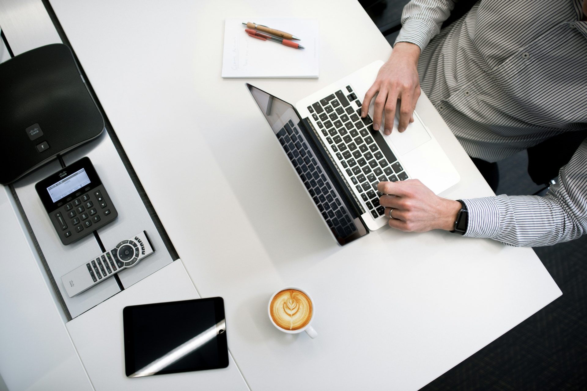 Person, die an einem weißen Holztisch einen Laptop benutzt